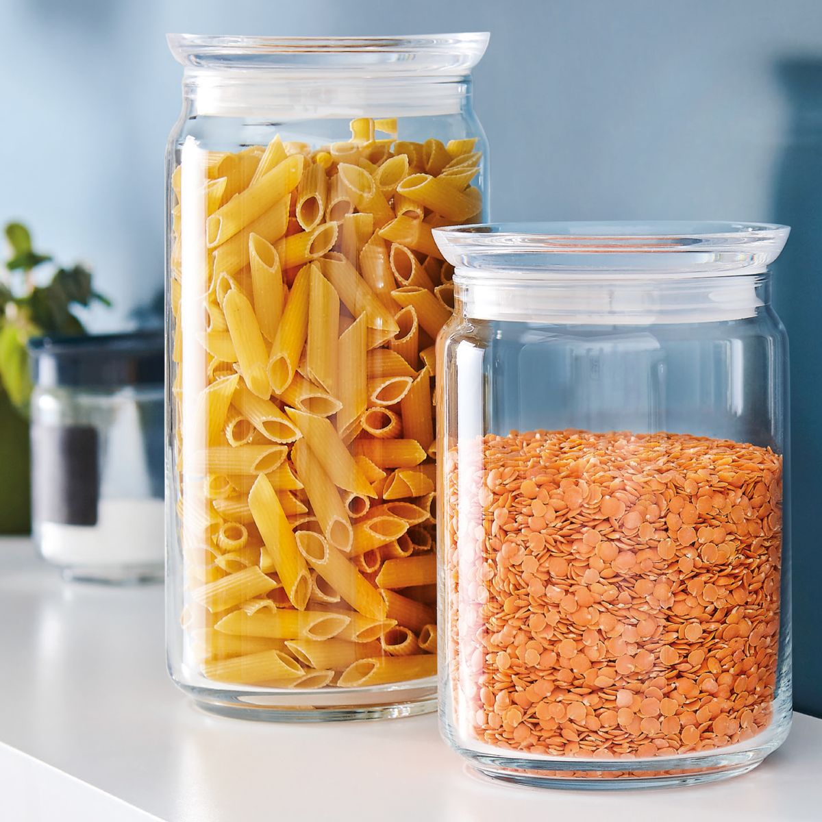 Glazen pot van 1,5 liter met vulling en logo in sfeerruimte, transparant voorraadglas als keukenaccessoire.