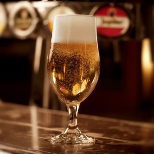 Bierglas Executive 26 cl. met bier gevuld en geplaatst op houten tafel in sfeervolle setting.
