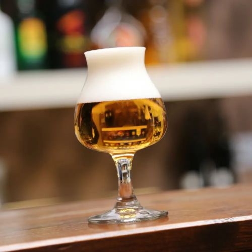 Gevuld bierglas Specials Tasting 25 cl. in sfeervolle setting, geplaatst op houten tafel.