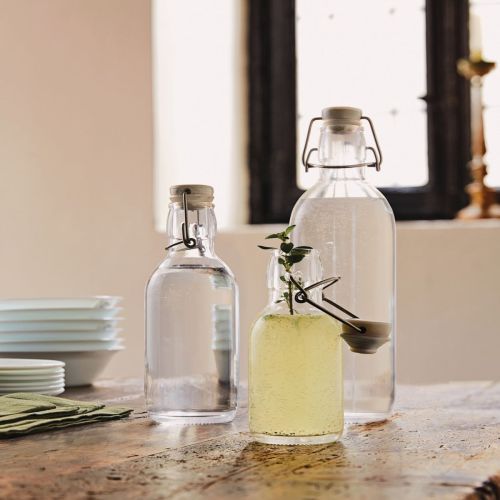 Emilia Fles 0,5 liter met logo op tafel in een warm verlichte omgeving.